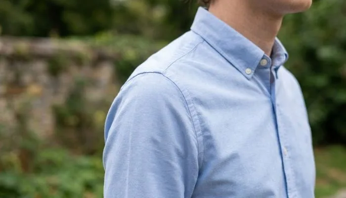 Close-up of a shirt shoulder seam sitting perfectly on the shoulder bone to demonstrate proper fit for skinny men.